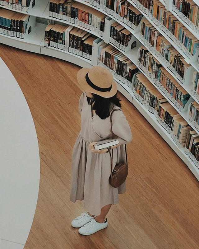 A visitor looking along the shelves of a curved library